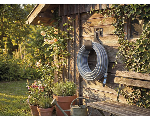 Scenă de grădină cu tambur pentru furtun pe perete de lemn, înconjurat de plante