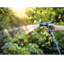 O persoană ține un pulverizator de grădină și udă plantele.