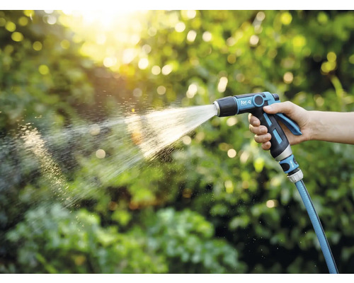 O persoană ține un pulverizator de grădină și udă plantele.