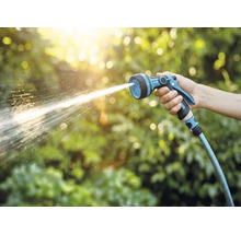 O mână ține un pulverizator de grădină din care țâșnește apă