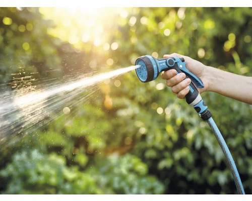 O mână ține un pulverizator de grădină din care țâșnește apă