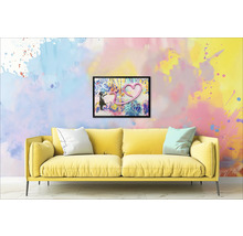 Canapea galbenă cu perne în fața unui perete cu o imagine încadrată a unei fete și a unei inimi