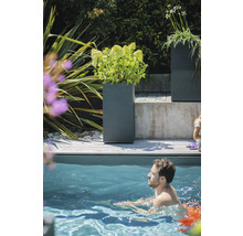 Scenă cu jardiniere gri pe o terasă de lemn lângă o piscină în care o persoană înoată