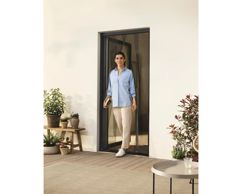 Femeie care trece printr-o ușă cu plasă de insecte spre o terasă cu plante