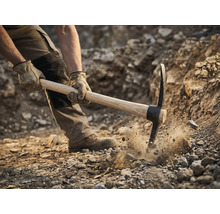 Bărbat folosind târnăcopul pentru a săpa în pământ