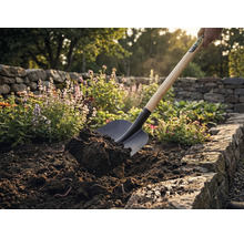 O lopată ridică pământul într-o grădină.