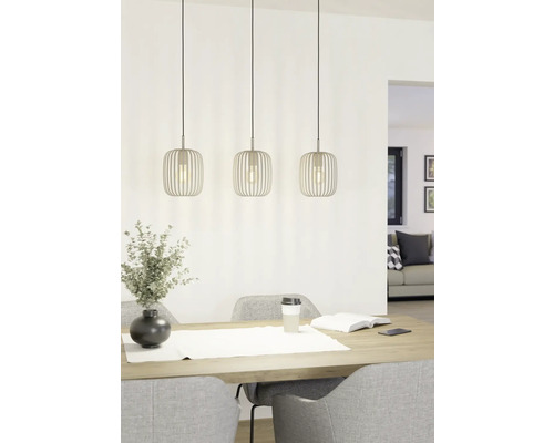 Trei lămpi suspendate metalice deasupra unei mese cu decorațiuni și scaune.