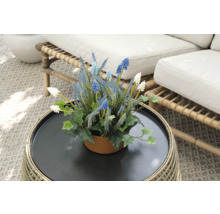 Flori artificiale decorative într-un ghiveci pe o masă de ratan