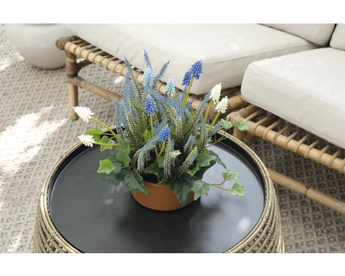 Flori artificiale decorative într-un ghiveci pe o masă de ratan