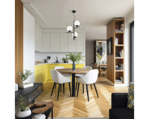 Bucătărie modernă cu zonă de luat masa, masă rotundă din lemn, scaune albe, pendul cu trei brațe și globuri de sticlă, dulapuri de bucătărie galbene.