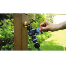 Robinet de grădină cu distribuitor de apă și furtun de grădină conectat în timpul utilizării.