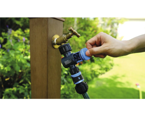 Robinet de grădină cu distribuitor de apă și furtun de grădină conectat în timpul utilizării.