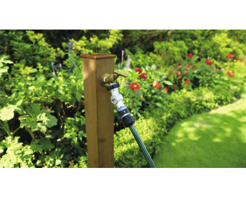 Scenă de grădină cu robinet și furtun de grădină pe un stâlp de lemn