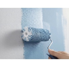 O persoană vopsește un perete cu o rolă de vopsea.