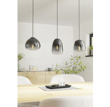 Trei lămpi suspendate din sticlă deasupra unei mese din lemn într-o cameră luminoasă