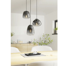 Trei lămpi suspendate din sticlă deasupra unei mese din lemn într-o cameră luminoasă