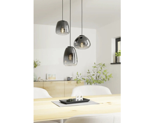 Trei lămpi suspendate din sticlă deasupra unei mese din lemn într-o cameră luminoasă