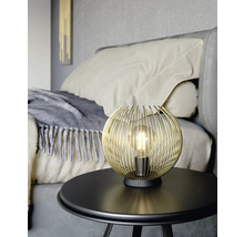 Lampa s glob de sârmă aurie pe o masă din dormitor