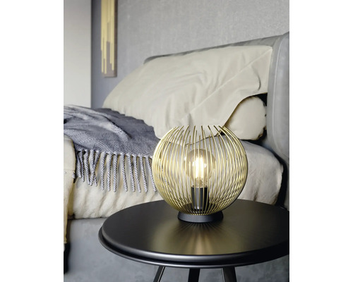 Lampa s glob de sârmă aurie pe o masă din dormitor