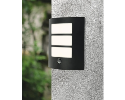 Lumină de perete neagră cu senzor de mișcare și trei ferestre de lumină dreptunghiulare pe un perete.