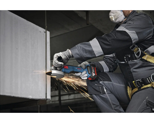 Un muncitor folosește un polizor unghiular fără fir pentru a șlefui metalul, rezultând scântei.