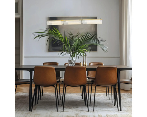 Sufragerie modernă cu masă din lemn închis, scaune din piele maro și pendulă cu trei abajururi din sticlă deasupra unei plante de palmier.