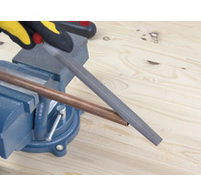 Un tub de cupru este prelucrat cu o pilă, care este fixată într-o menghină.