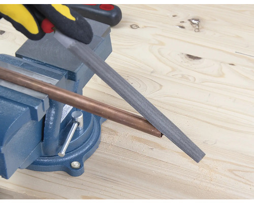 Un tub de cupru este prelucrat cu o pilă, care este fixată într-o menghină.