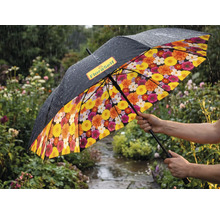 Umbrelă într-o grădină ploioasă cu exterior negru, FloraSelf Logo și model floral colorat pe interior.