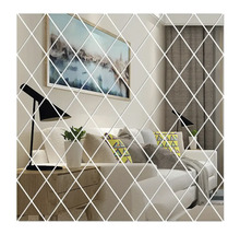 Oglindă de perete din plăci de oglindă în formă de romb care reflectă o sufragerie luminoasă cu o canapea albă și o măsuță din lemn.