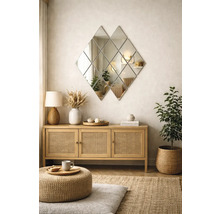 Living modern cu o oglindă de perete în formă de romb deasupra unei comode din lemn cu uși din ratan și decorațiuni naturale.