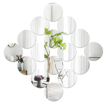 Set de 13 oglinzi de perete rotunde în formă de romb care reflectă plante și piese de mobilier.