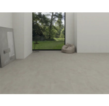 Cameră modernă și luminoasă, cu pardoseală din vinil gri deschis cu aspect de beton, fereastră mare cu vedere la grădină și un puf.