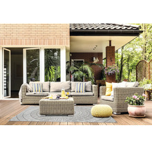 Terasă luminoasă cu set de mobilier din ratan gri, covor de exterior cu model circular, puf galben împletit și plantă la ghiveci pe podea din lemn.