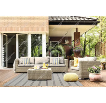 Set modern de mobilier de grădină din poliratan gri cu canapea, fotoliu și măsuță pe o terasă din lemn cu covor de exterior în dungi.