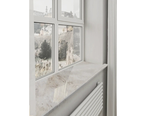 Pervaz de fereastră deschis la culoare cu aspect de piatră naturală sub o ramă de fereastră albă cu vedere spre ziduri istorice.