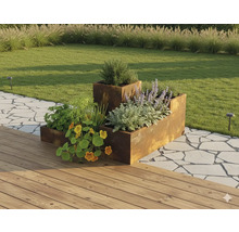 Strat înălțat modular din oțel Corten într-o grădină cu plante, lângă o terasă din lemn și o potecă din piatră.