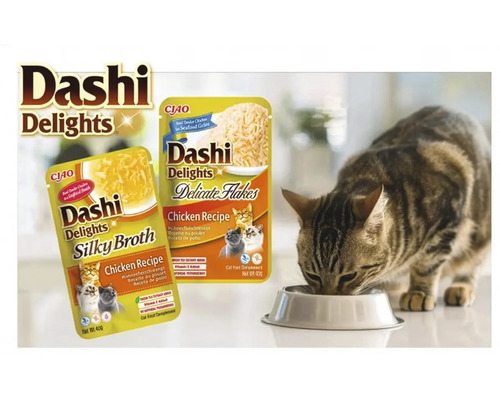 Pisică mâncând dintr-un bol lângă hrana pentru pisici Dashi Delights Chicken Recipe Silky Broth și Delicate Flakes.