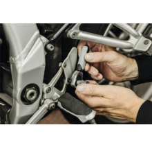 Mâini utilizând un clichet mic cu cheie tubulară pentru o reparație la o motocicletă.