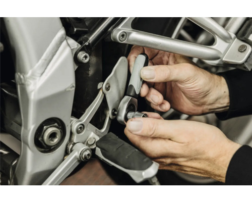 Mâini utilizând un clichet mic cu cheie tubulară pentru o reparație la o motocicletă.
