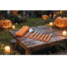 Set de șapte piese pentru sculptat dovleci cu mânere portocalii și husă pe o masă din lemn cu dovleci de Halloween luminați și lumânări.