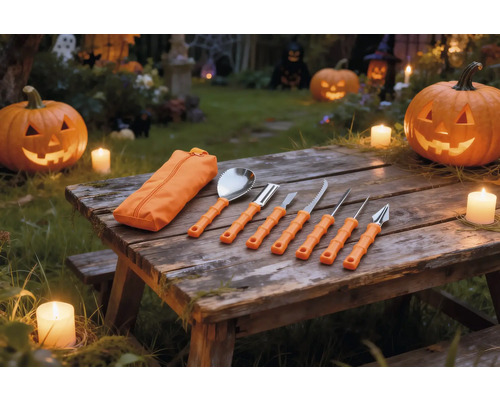 Set de șapte piese pentru sculptat dovleci cu mânere portocalii și husă pe o masă din lemn cu dovleci de Halloween luminați și lumânări.