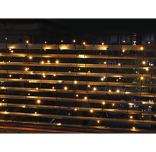 Ghirlandă luminoasă cu LED-uri alb cald pe o balustradă la exterior pe timp de noapte.