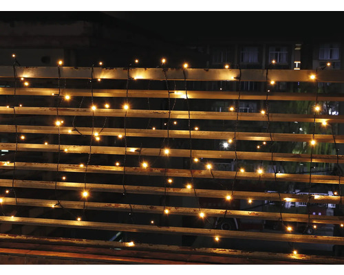 Ghirlandă luminoasă cu LED-uri alb cald pe o balustradă la exterior pe timp de noapte.