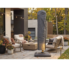 Husă de protecție gri pentru umbrelă suspendată pe o terasă modernă cu mobilier de grădină, masă cu focar și ghirlandă luminoasă.