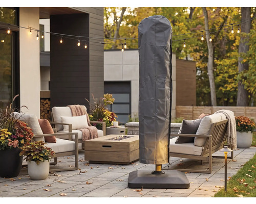 Husă de protecție gri pentru umbrelă suspendată pe o terasă modernă cu mobilier de grădină, masă cu focar și ghirlandă luminoasă.