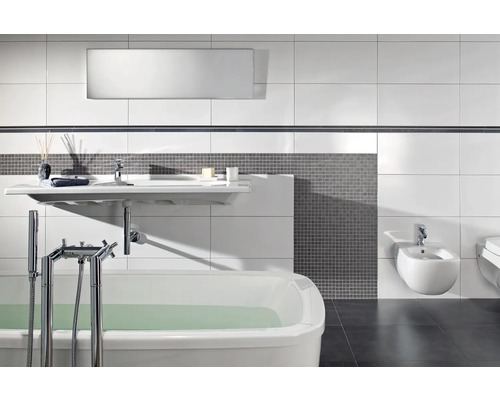 Baie modernă cu cadă albă, lavoar suspendat și bidet, mozaic gri și plăci ceramice albe de mari dimensiuni pentru perete.