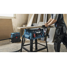 Fierăstrău circular cu masă Bosch Professional GTS 254 tăind lemn cu un aspirator universal Bosch conectat într-un atelier.