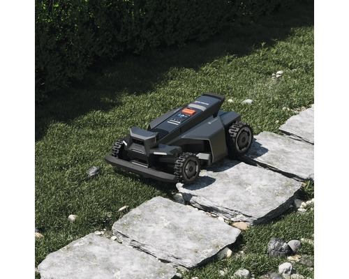 Robot de tuns gazonul Segway Navimow circulând pe o cărare din dale de piatră într-o grădină.