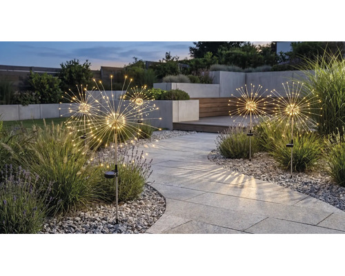 Lămpi solare pentru grădină cu design păpădie și diode luminoase, de-a lungul unei alei pavate într-o grădină modernă la amurg.